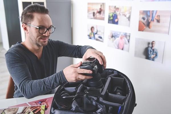 man packing camera bag