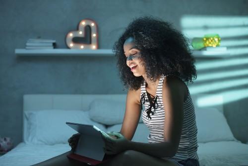 woman looks at tablet at night