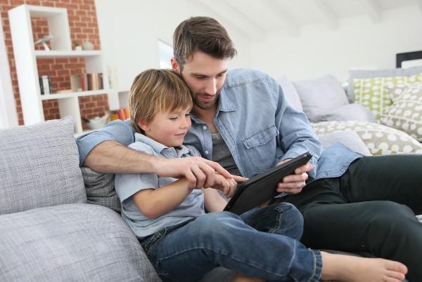 father and son using a tablet in the living room