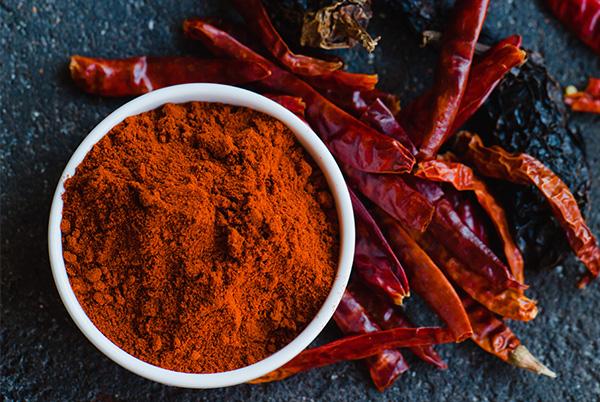 a bowl of chili powder and red chili peppers on a table