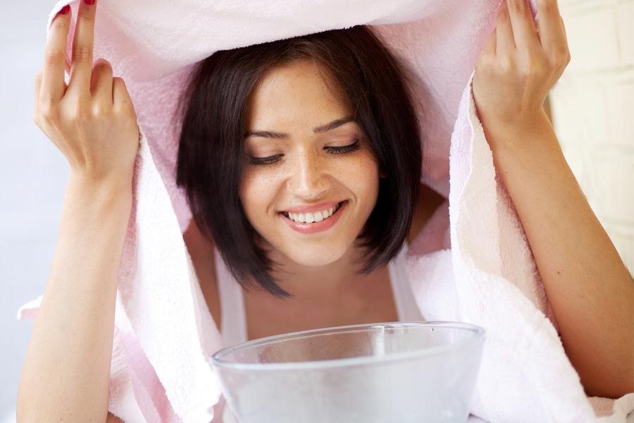 a woman with curly hair holding a facial steamer to her face