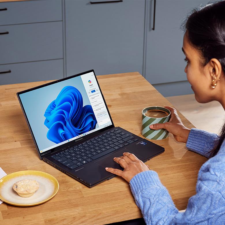 a woman sitting at a table with a mug and a laptop