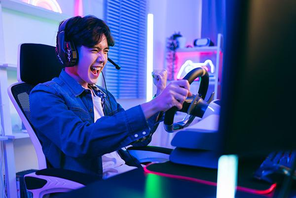 Young man playing racing wheel game