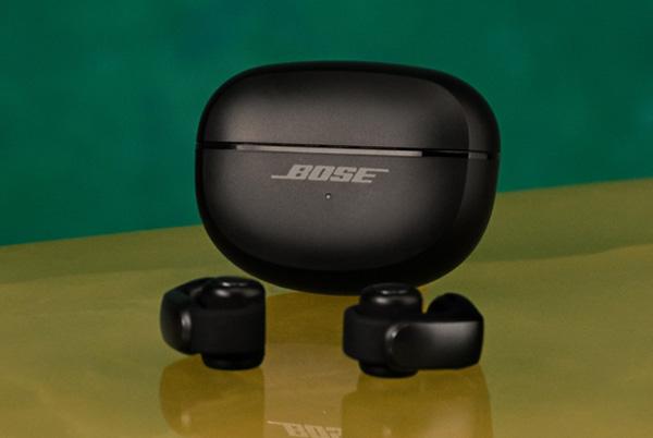 a pair of black bose ultra open earbuds sitting on top of a yellow table