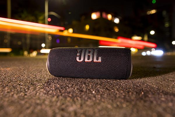 a jbl flip 6 portable speaker sitting on the ground in the middle of the street