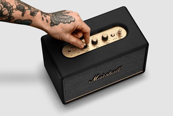 a man with a tattoo on his hand touching a marshall action iii bluetooth speaker