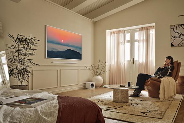 a man sitting in a chair in a room with a large samsung the frame pro tv on the wall