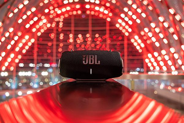 jbl xtreme 4 portable speaker on table with red lights in background