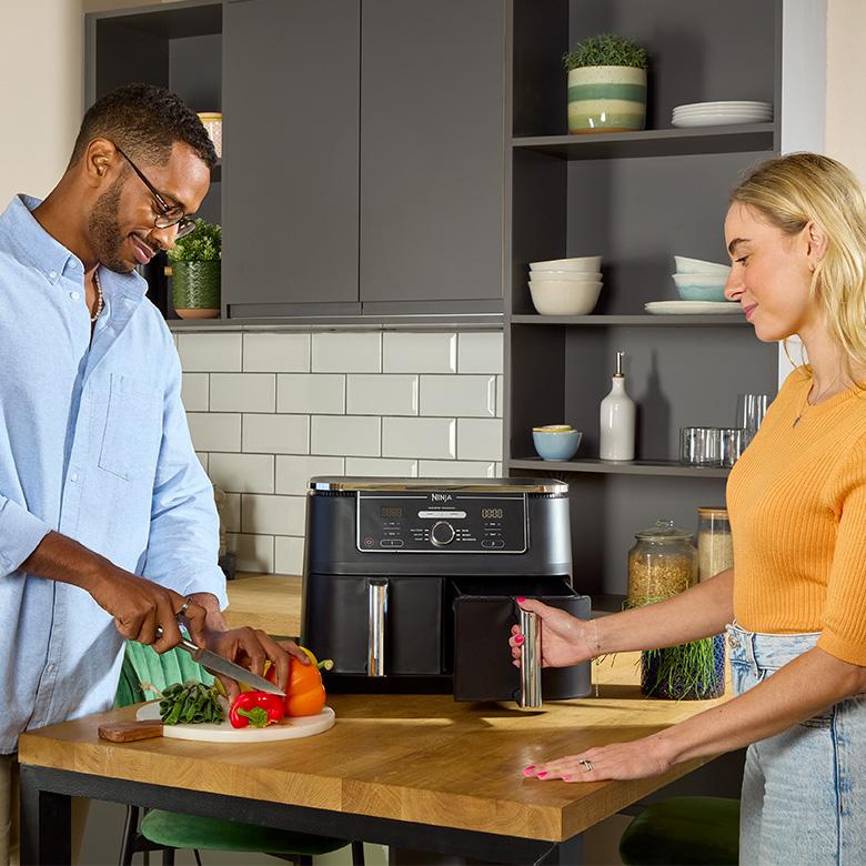 a man and woman preparing food in a kitchen with an air fryer