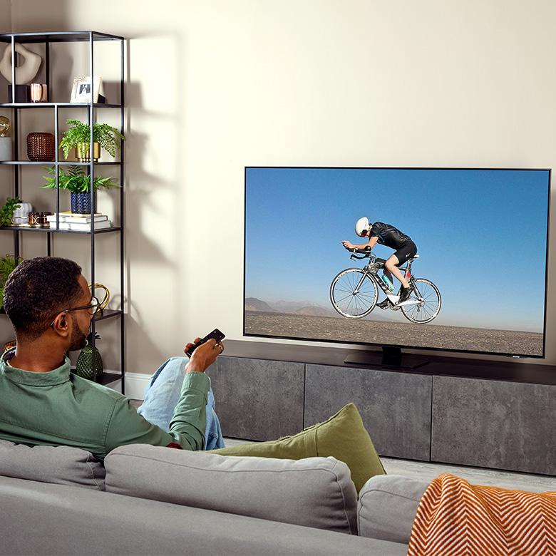 a man sitting on a couch watching a man on a bicycle