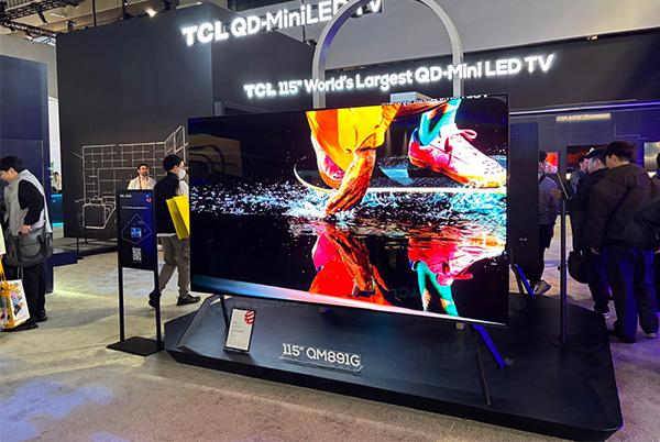a large tv on display at a trade show with people around it