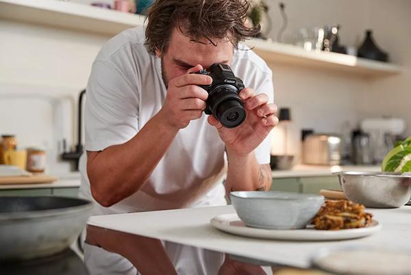 a man taking a picture of food on a table with a camera