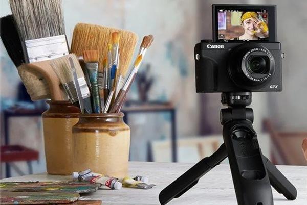 a person holding a camera on a tripod next to a painting