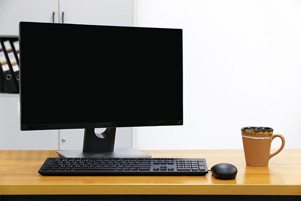 a desktop computer monitor, keyboard, mouse and coffee cup on a desk