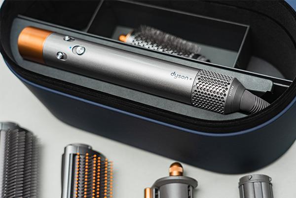 a dyson airwrap case with a brush, comb, and other hair tools inside