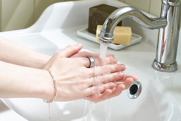 a person washing their hands in a sink wearing a smart ring