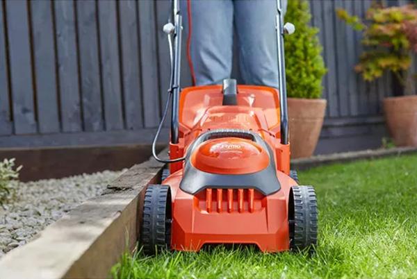 a person is using an orange and black lawn mower to cut grass