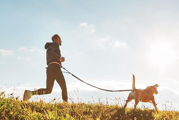 Man running with dog outside sun