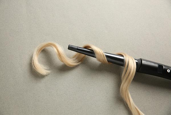 a black hair curler with a long piece of blonde hair attached