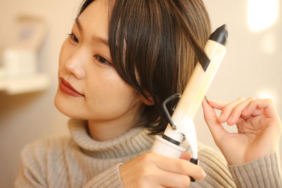 a woman with long blonde hair is using a hair curler
