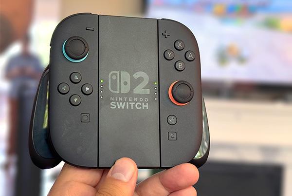 a person holding a black game controller in their hand