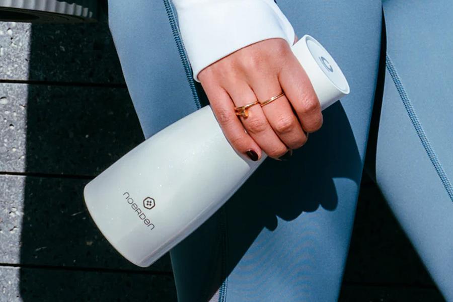 a woman in white pants holding a smart water bottle