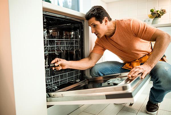 man repairing dishwasher screwdriver