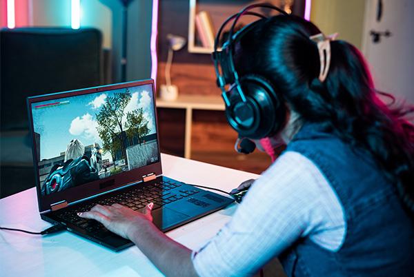 a woman wearing headphones playing a video game on a laptop