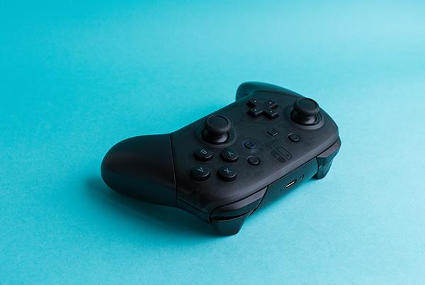 a black nintendo switch pro controller on blue background