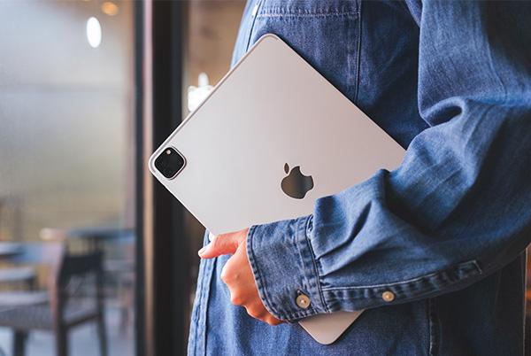 a person holding ipad under their arm while standing in a room