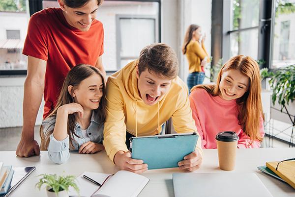 a group of kids looking at a tablet together in a classroom