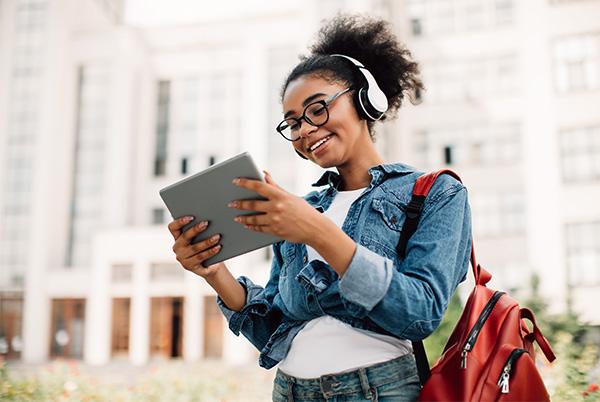 a young woman with headphones and a backpack is using a tablet