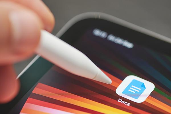a person holding a pen over a tablet screen with a docs apps