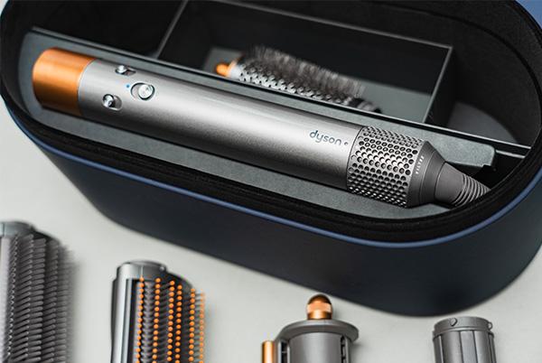 a silver dyson airwrap sitting in its case with various attachments in front of it