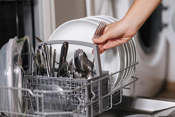 a person placing a fork in a dishwasher cutlery basket