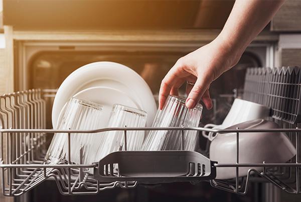a person is putting glasses in the dishwasher in the kitchen