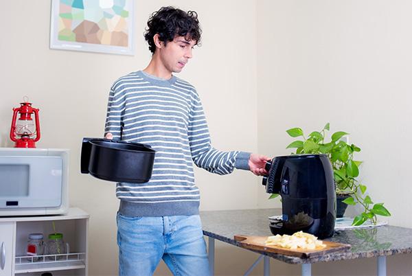 a man in striped shirt holding an air fryer basket