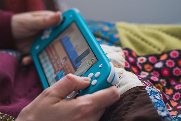 a person holding a blue nintendo switch lite in their hands
