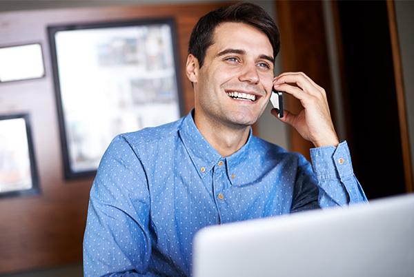 Man talking iPhone desk laptop