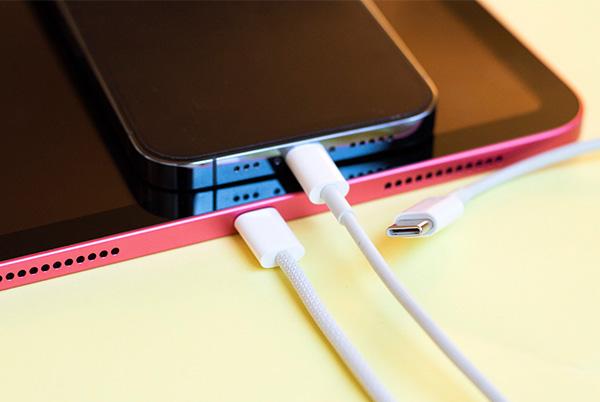 a close up of an iphone and ipad charging with cables plugged in