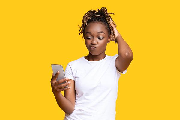 Woman confused scratching head looking at phone