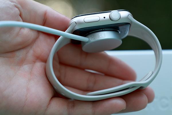 a person holding an apple watch in their hand with a charging cord attached