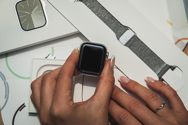 a woman holding an apple watch in her hands with a box of apple products