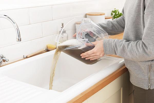 a person pouring water into a sink from a carpet cleaner tank