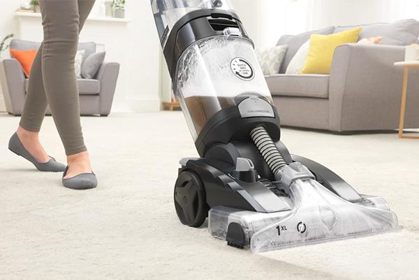 a woman is using a carpet cleaner in a room