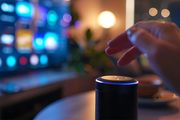 a person holding a small speaker in front of a tv