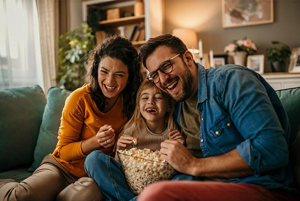 a family sitting on a couch eating popcorn