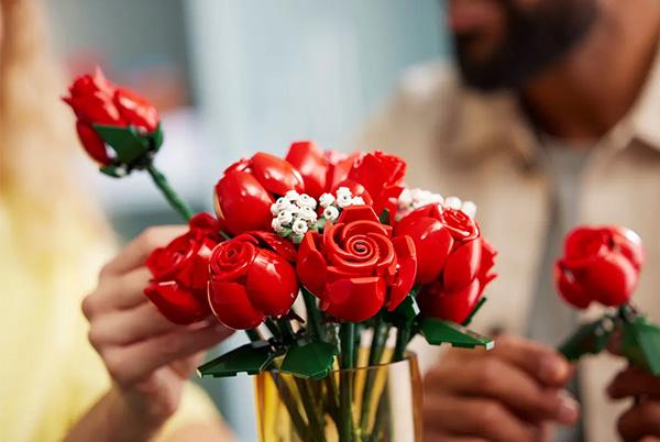 a man and woman holding a vase with lego botanicals bouquet of roses