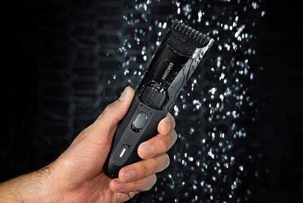 a man is holding a black hair clipper in his hand