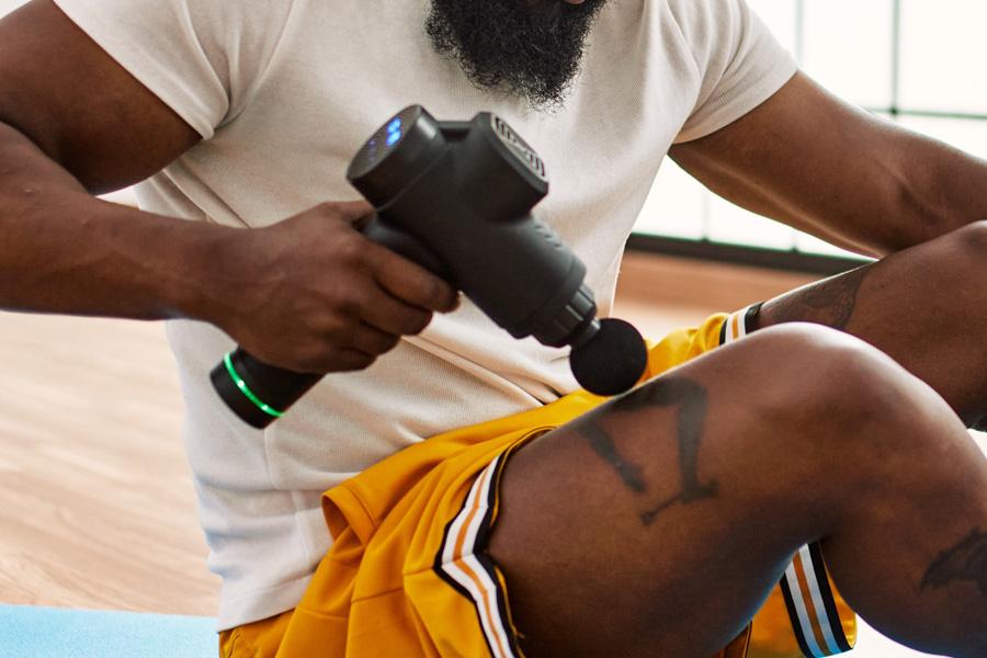 a man is working out on a mat with a massage gun